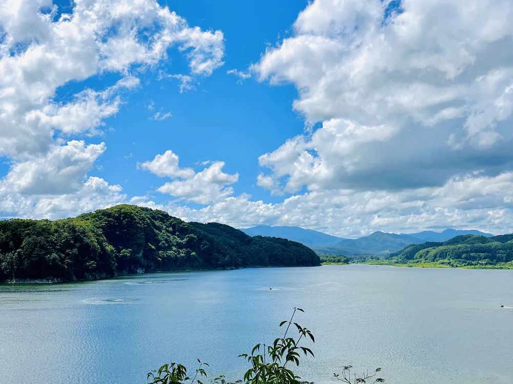 青空と雲の下、緑の山にかこまれた湖